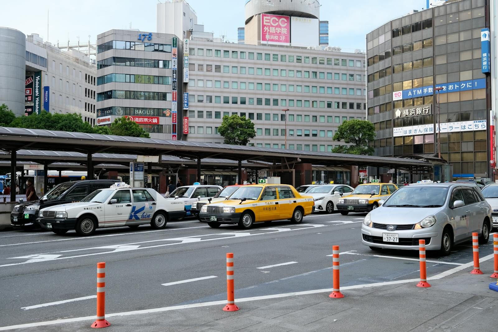 A lively street scene in Yokohama, Japan showing multiple taxis and city buildings.