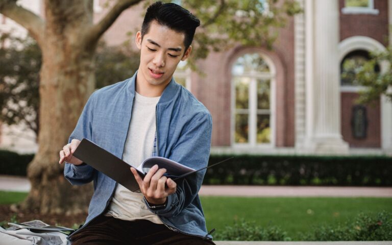 Sinh viên đọc và kiểm tra tài liệu tại khuôn viên trường trước khi hoàn thiện hồ sơ