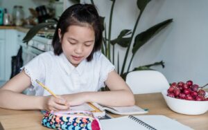Học sinh châu Á viết ghi chú trong vở khi học bảng chữ cái tiếng Nhật.