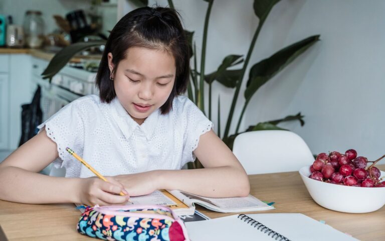 Học sinh châu Á viết ghi chú trong vở khi học bảng chữ cái tiếng Nhật.