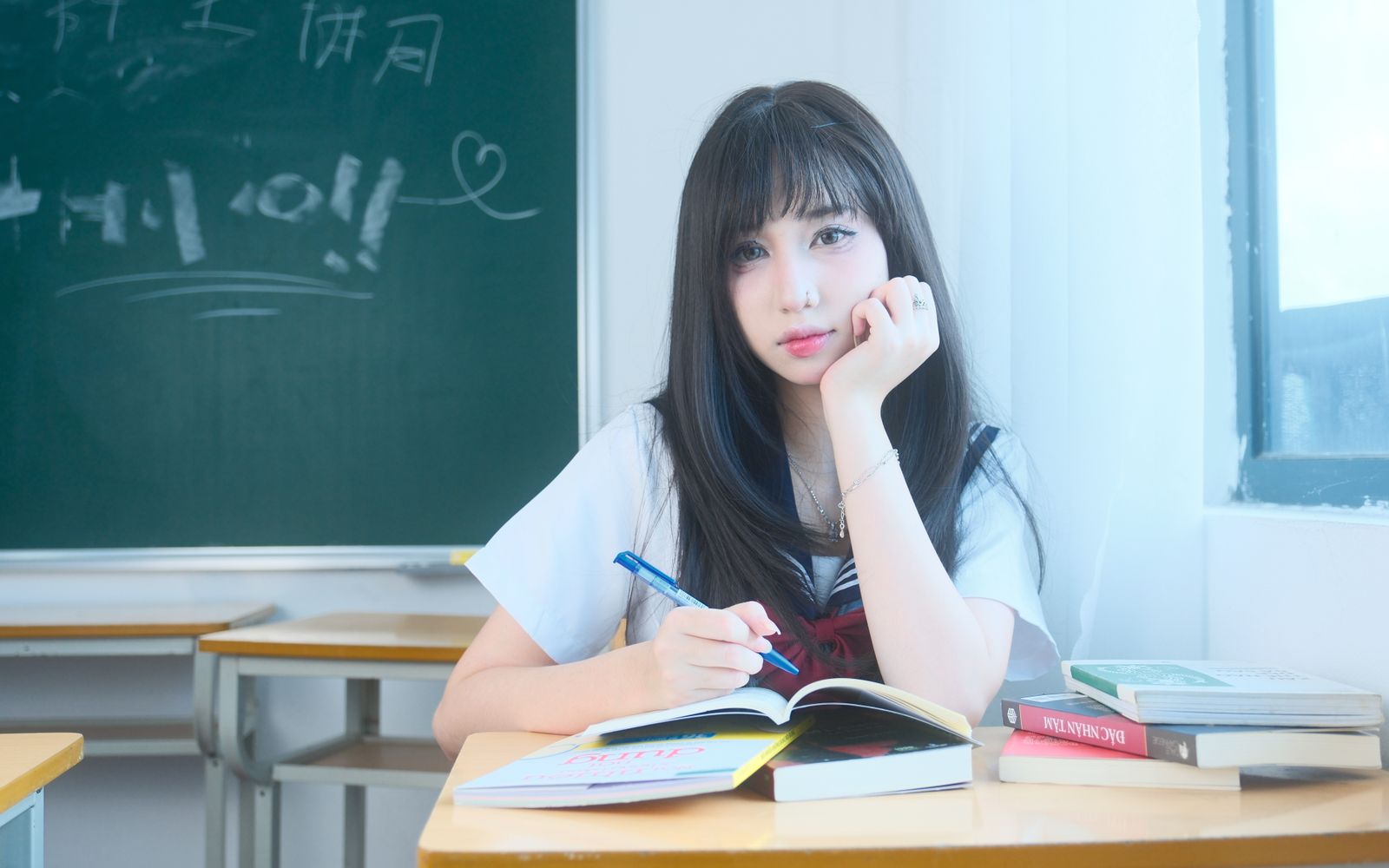 Cách học bảng chữ cái tiếng Nhật nhanh nhớ: Hiragana & Katakana trong 7 ngày 2 Học sinh châu Á luyện viết trong vở tại lớp học, minh họa bước tự gọi lại và viết Kana từ trí nhớ.